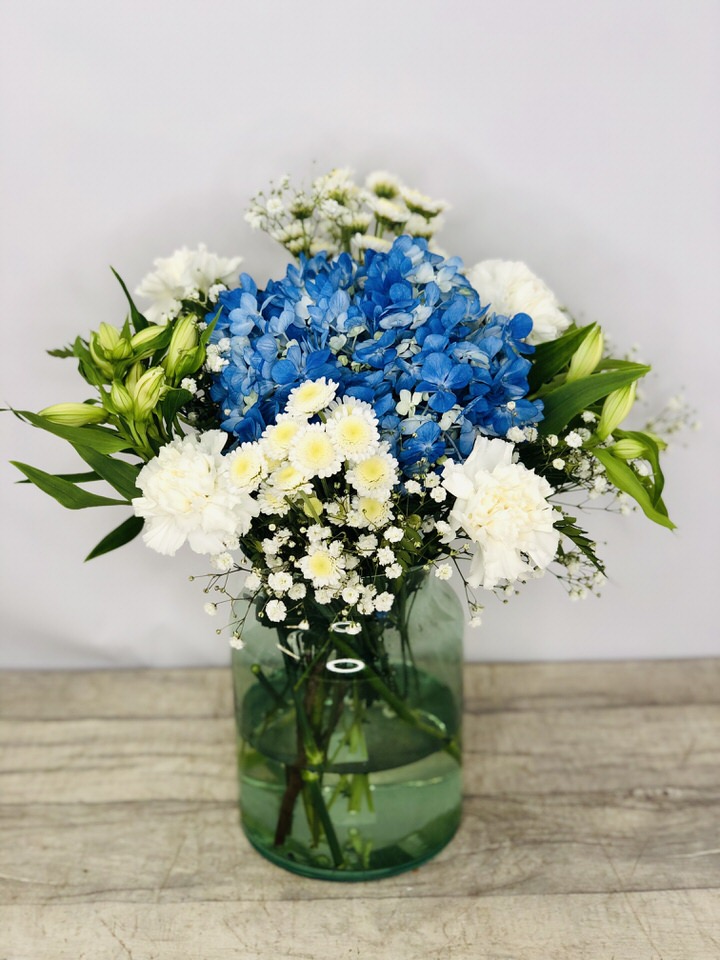 <h2>Vase of Blue Fresh Flowers - Hand Delivered</h2>
<p>These beautiful blue and white flowers hand-arranged by our professional florists into an eco-friendly glass vase are a delightful choice from our new collection. This vase contains lots of classic favourites and it would make the perfect gift to celebrate any occasion or to let someone know you are thinking of them. </p>
<h2>Flower Delivery Coverage</h2>
<p>Our shop delivers flowers to the following Liverpool postcodes L1 L2 L3 L4 L5 L6 L7 L8 L11 L12 L13 L14 L15 L16 L17 L18 L19 L24 L25 L26 L27 L36 L70 If your order is for an area outside of these we can organise delivery for you through our network of florists. We will ask them to make as close as possible to the image but because of the difference in stock and sundry items, it may not be exact.</p>
<h2>Vase of Flowers | Flowers in a Vase</h2>
<p></p>
<p>The advantage of having an arrangement made this way is that they are artfully arranged by our florists into the vase so that they stay in the display.</p>
<p>Being delivered in a vase and in water means the recipient does not need to arrange the flowers themselves, they can just put them down and enjoy.</p>
<p>Includes 1 Green Tinted Vase, 1 Blue Hydrangea, 4 White Carnations, Gypsy Grass, 2 White Alstro, and 3 White Stallion together with mixed seasonal foliage.</p>
<h2>Eco-Friendly Liverpool Florists</h2>
<p>As florists we feel very close earth and want to protect it. Plastic waste is a huge problem in the florist industry so we made the decision to make our packaging eco-friendly.</p>
<p>To achieve this, we worked with our packaging supplier to remove the lamination off our boxes and wrap the tops in an Eco Flowerwrap, which means it easily compostable or can be fully recycled.</p>
<p>Once you've finished enjoying your flowers from us, they will go back into growing more flowers! Only a small amount of plastic is used as a water bubble and this is biodegradable.</p>
<p>Even the sachet of flower food included with your bouquet is compostable.</p>
<p>All our bouquets have small wooden ladybird hidden amongst them, so do not forget to spot the ladybird and post a picture on our social media pages to enter our rolling competition.</p>
<h2>Flowers Guaranteed for 7 Days</h2>
<p>Our 7-day freshness guarantee should give you confidence that we will only send out good quality flowers.</p>
<p>Leave it in our hands we will create a marvellous bouquet which will not only look good on arrival but will continue to delight as the flowers bloom.</p>
<h2>Liverpool Flower Delivery</h2>
<p>We are open 7 days a week and offer advanced booking flower delivery, same-day flower delivery, 3-hour flower delivery. Guaranteed AM PM or Evening Flower Delivery and also offer Sunday Flower Delivery.</p>
<p>Our florists deliver in Liverpool and can provide flowers for you in Liverpool, Merseyside. And through our network of florists can organise flower deliveries for you nationwide.</p>
<h2>The Best Florist in Liverpool, your local Liverpool Flower Shop</h2>
<p>Come to Booker Flowers and Gifts Liverpool for your beautiful flowers and plants. For that bit of extra luxury, we also offer a lovely range of finishing touches, such as wines, champagne, locally crafted Gin and Rum, vases, Scented Candles and Chocolates that can be delivered with your flowers.</p>
<p>To see the full range, see our extras section.</p>
<p>You can trust Booker Flowers and Gifts of delivery the very best for you.</p>
<p><em>5 Star review on Yell.com</em></p>
<p><em>Thank you Gemma for your fabulous service. The flowers are of the highest quality and delivered with a warm smile. My sister was delighted. Ordering was simple and the communications were top-notch. I will definitely use your services again.</em></p>